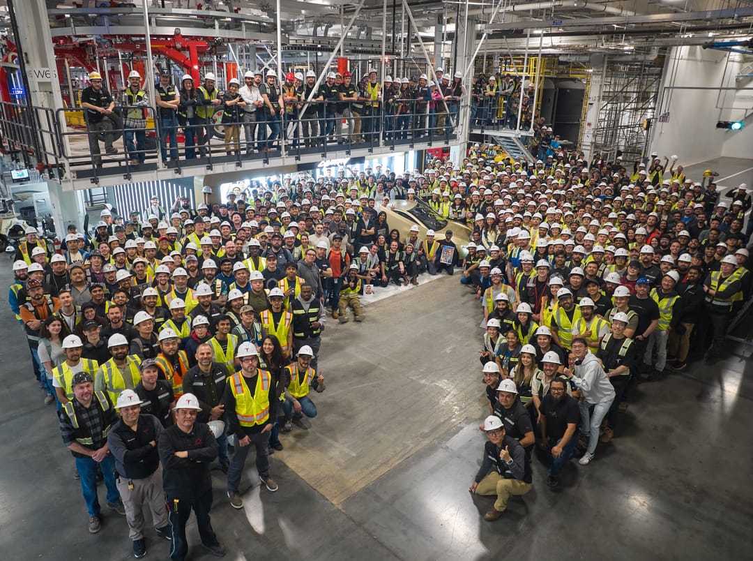 Factory workers gathered around the first production Cybercab at Giga Texas