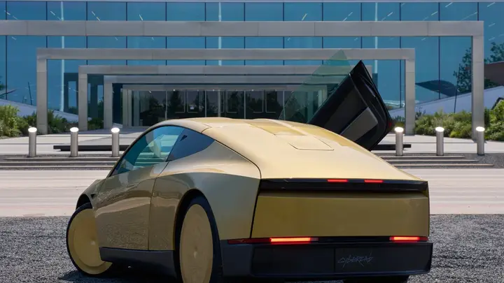 Gold Cybercab with a door open outside a Tesla building