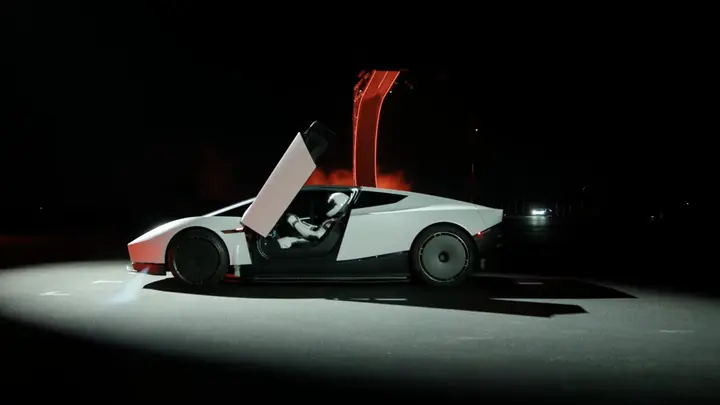 The new Tesla Roadster under a spotlight with its doors up