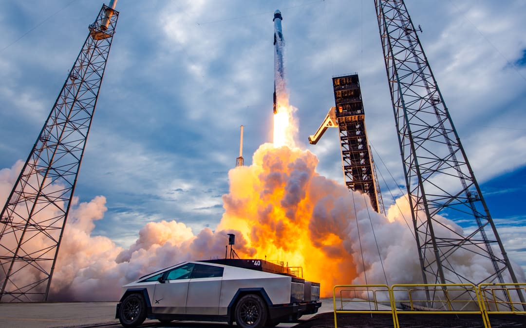 Cybertruck parked between launch towers as a rocket lifts off behind it