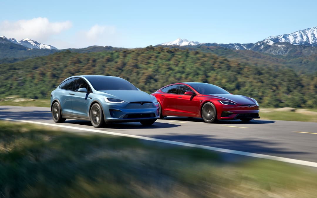 Blue Model X and red Model S driving on a mountain road