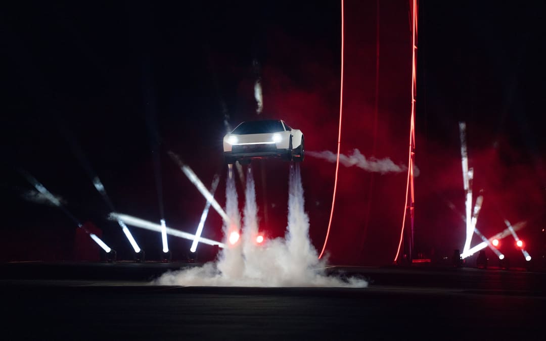 Roadster lifted on its thruster plumes at the night demo, lasers behind